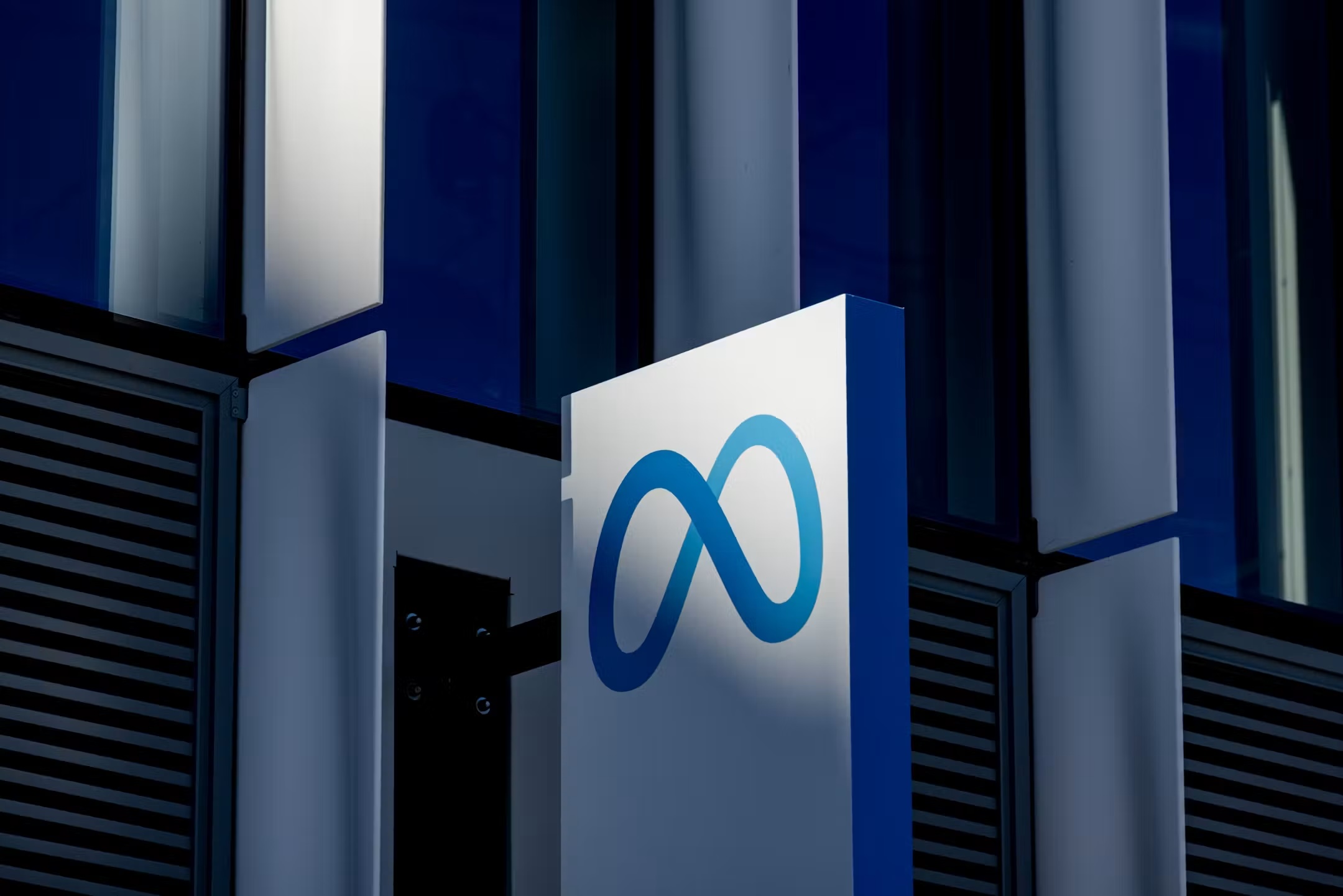 Close-up of a modern building facade with white panels and a blue infinity symbol partially visible